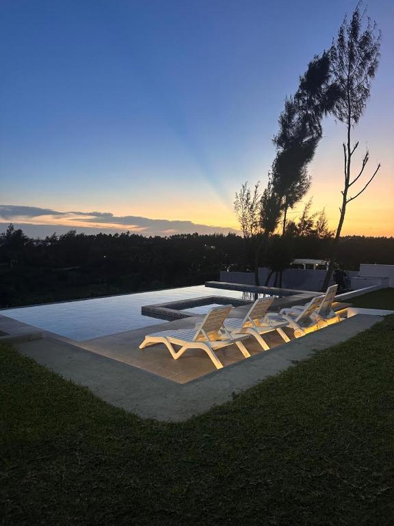 a group of white chairs sitting on a pool at Dzixile in Gueima