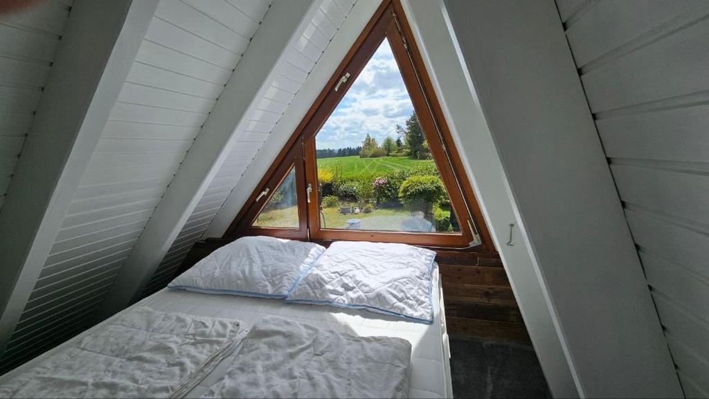 a bed in a room with a large window at Chalet in Freilingen Blankenheim mit Seenähe mitten in der Natur in Blankenheim