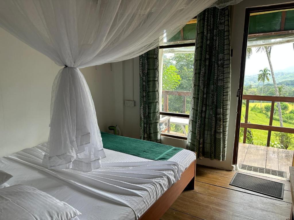 a bedroom with a bed and a large window at Kenath Paddy Cabin in Bopana
