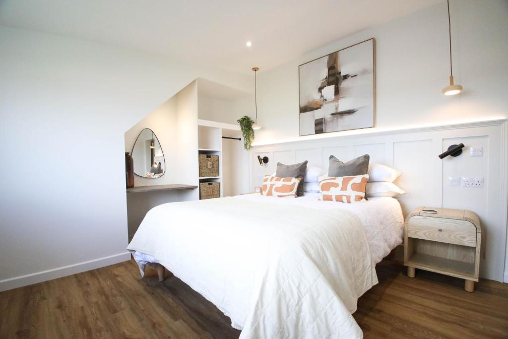 a white bedroom with a large white bed with pillows at Abode Above at Tor View in Padstow