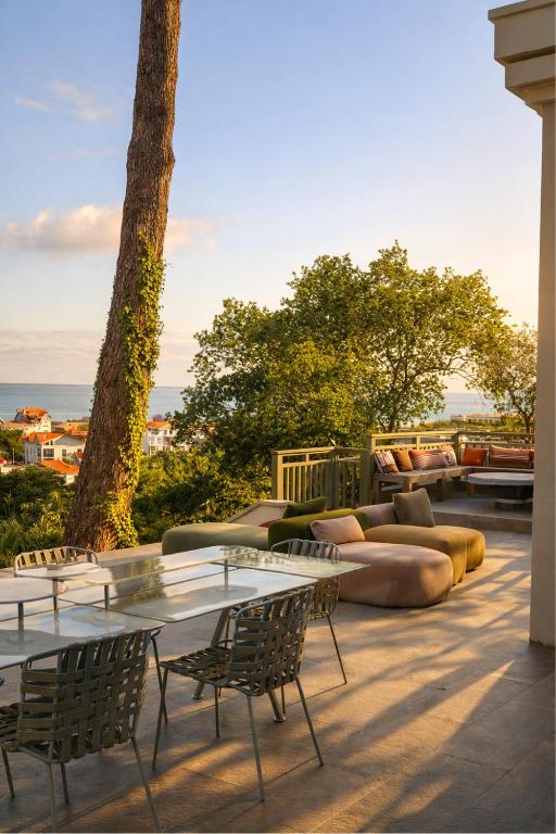 a patio with a couch and tables and chairs at Les Villas de la Ville d'Hiver Palissy et Velleda in Arcachon