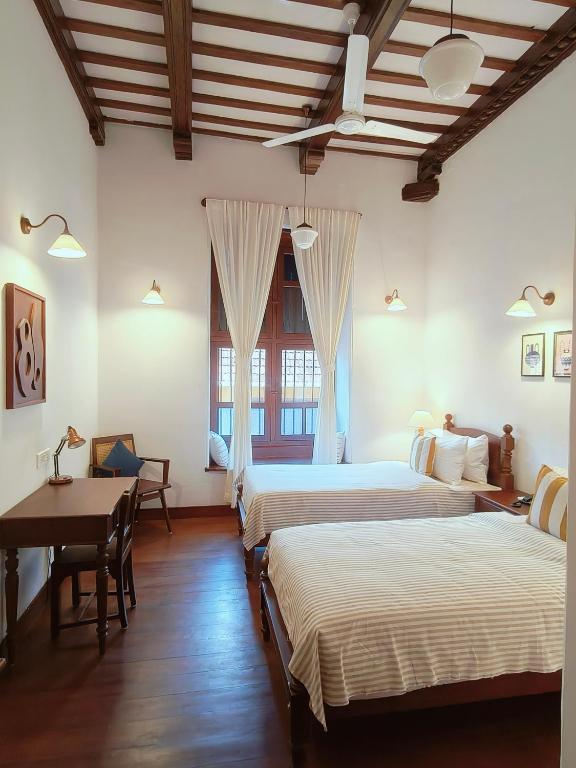 a room with three beds and a table and a desk at Ezekiel House Residence in Cochin