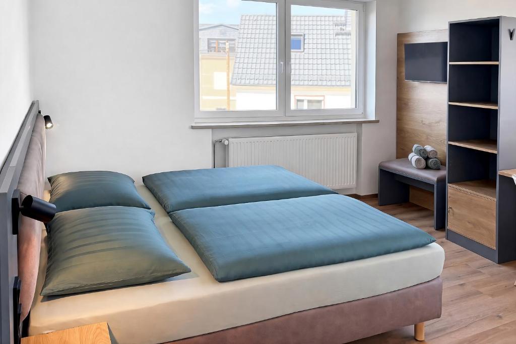 ein Bett mit blauen Kissen in einem Zimmer mit Fenster in der Unterkunft Kleiner Wolf in Wachau