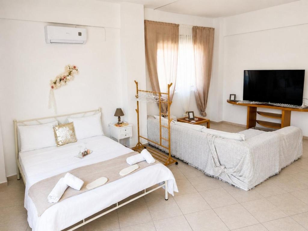 a bedroom with a bed and a couch and a tv at Studio Malades, Heraklion in Maládhes