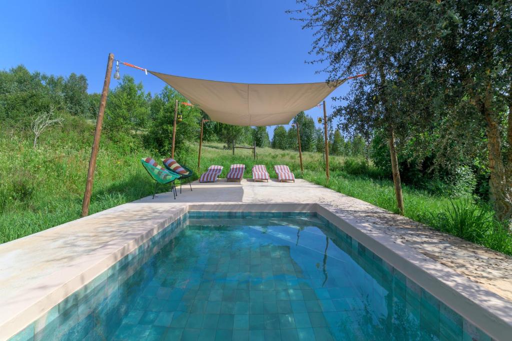 a pool with two chairs and a hammock next to at Eclectic Monte Laginha Alentejo in Aldeia do Cano