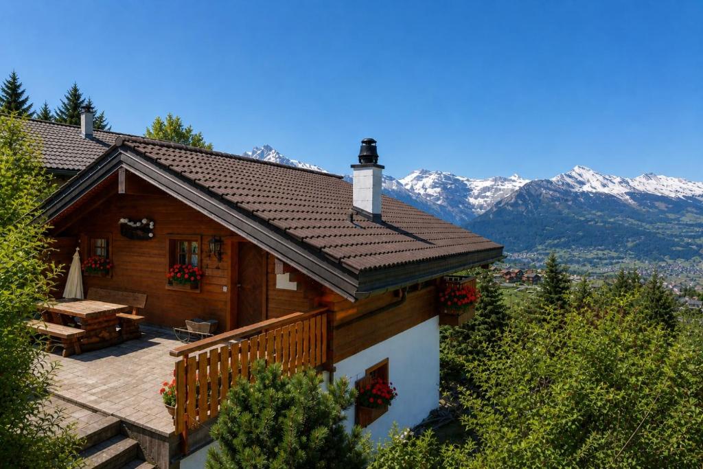 a house with a deck and mountains in the background at Chalet le Joyau in Nendaz - Sleeps 6 - Panoramic Views - 4 Vallées in Nendaz