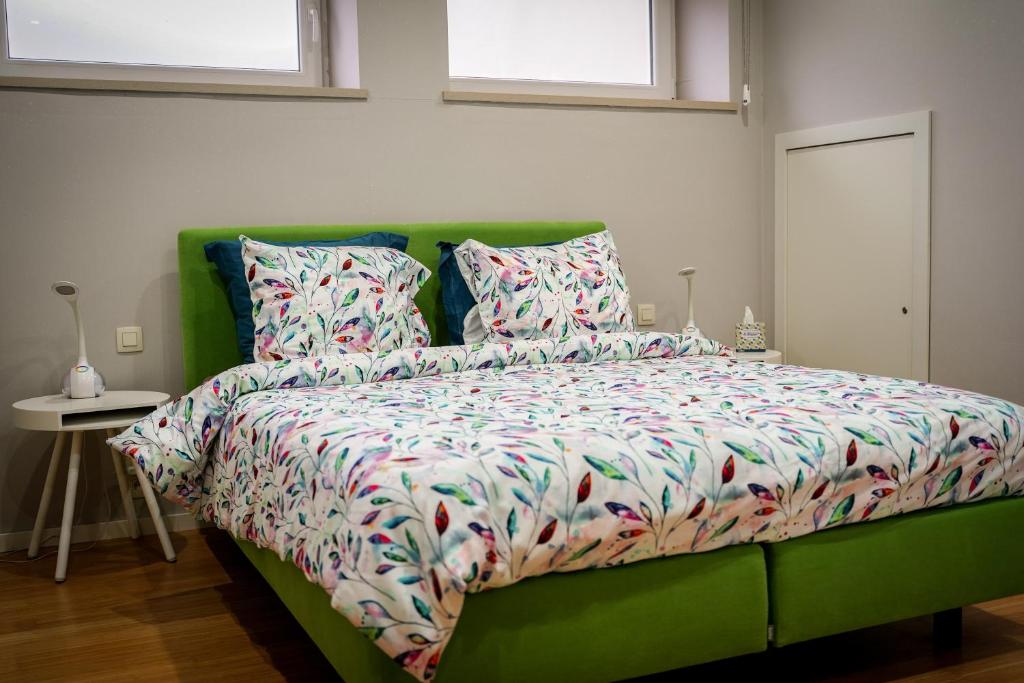 a green bed with a colorful comforter and two pillows at IDDup Atrium in Oreye