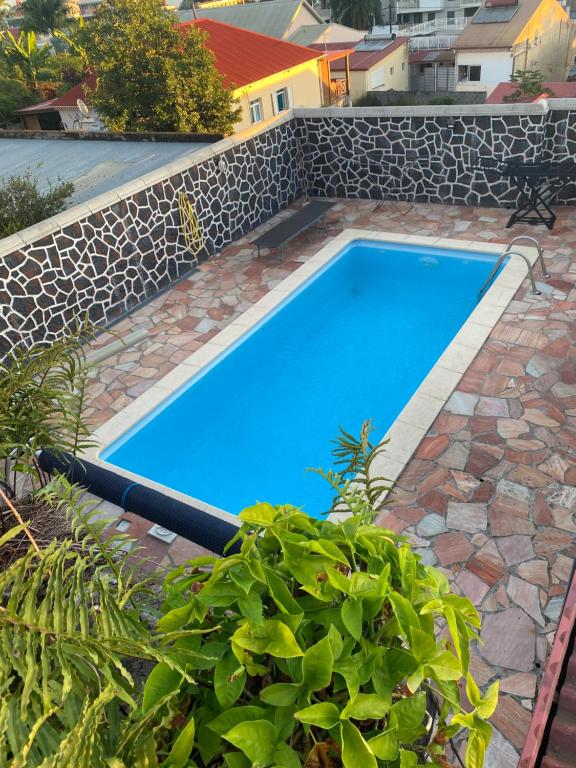 a large blue swimming pool next to a stone wall at pti caze Hoarau in Le Tampon