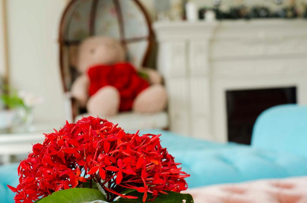 a vase of red flowers on a table with a doll at Bliss Bed and Breakfast in Yuchi