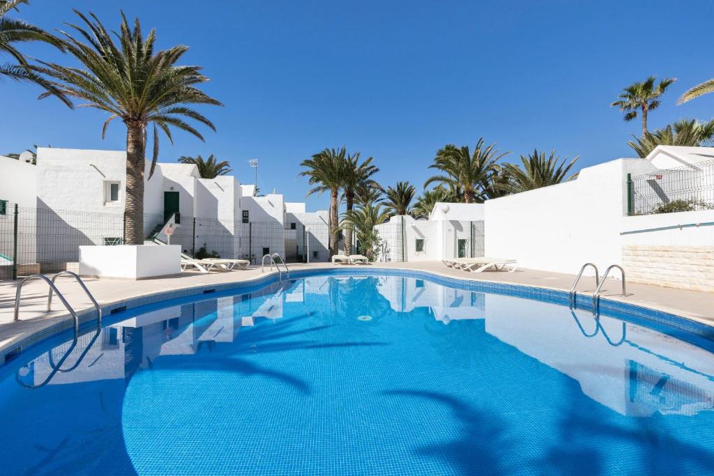 a swimming pool with palm trees and white buildings at Heiwa Apartment With Pool in Costa Calma
