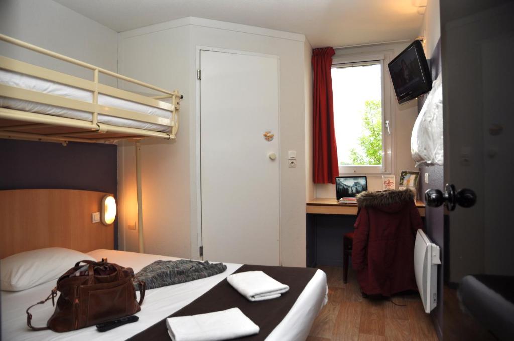 um quarto com uma cama e uma secretária com um saco. em Premiere Classe Niort Est - Chauray em Niort