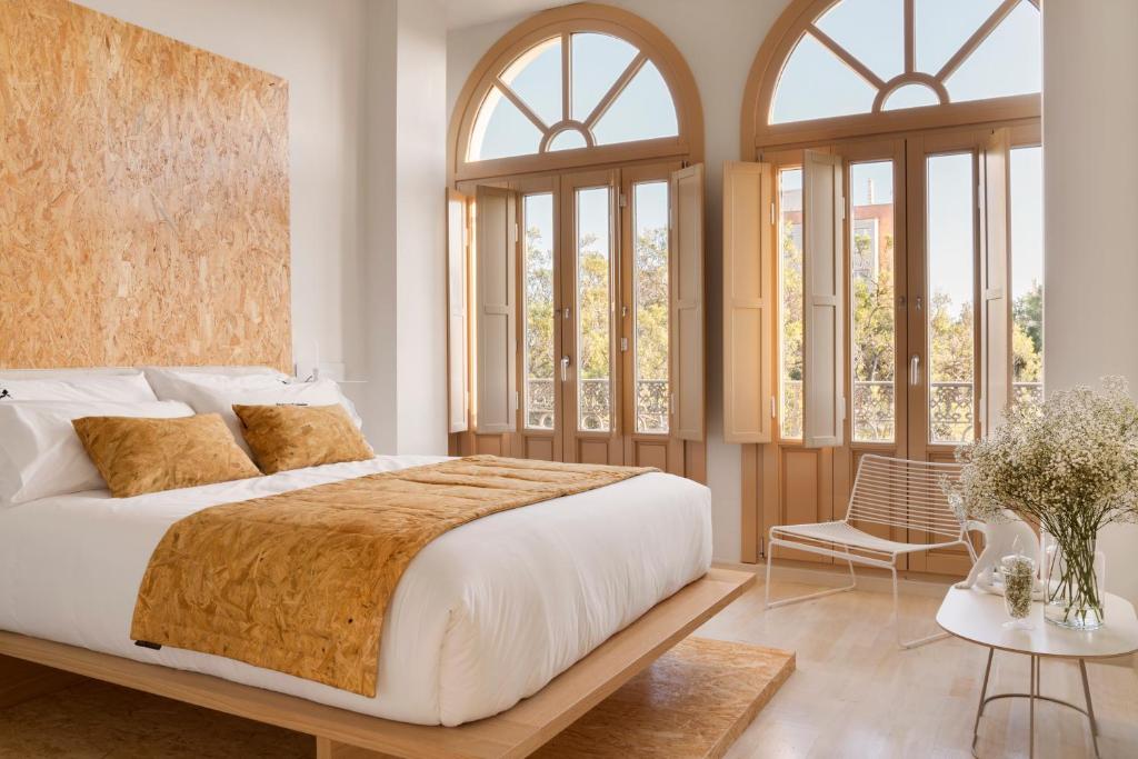 a bedroom with a large bed and windows at Halcyon Days designer apartments by Ana Locking in Málaga