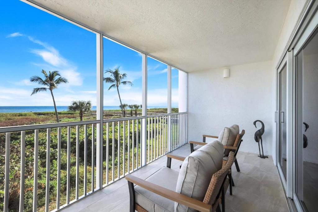 a balcony with views of the ocean and palm trees at Beachcomber A101 in Sanibel