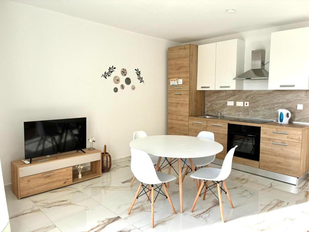 a kitchen with a table and chairs and a tv at Il-Pitirross Apartment Gozo in Sannat