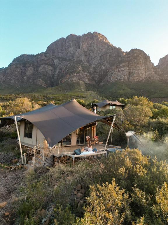 a house with a tent with a mountain in the background at Camp Canoe in Franschhoek