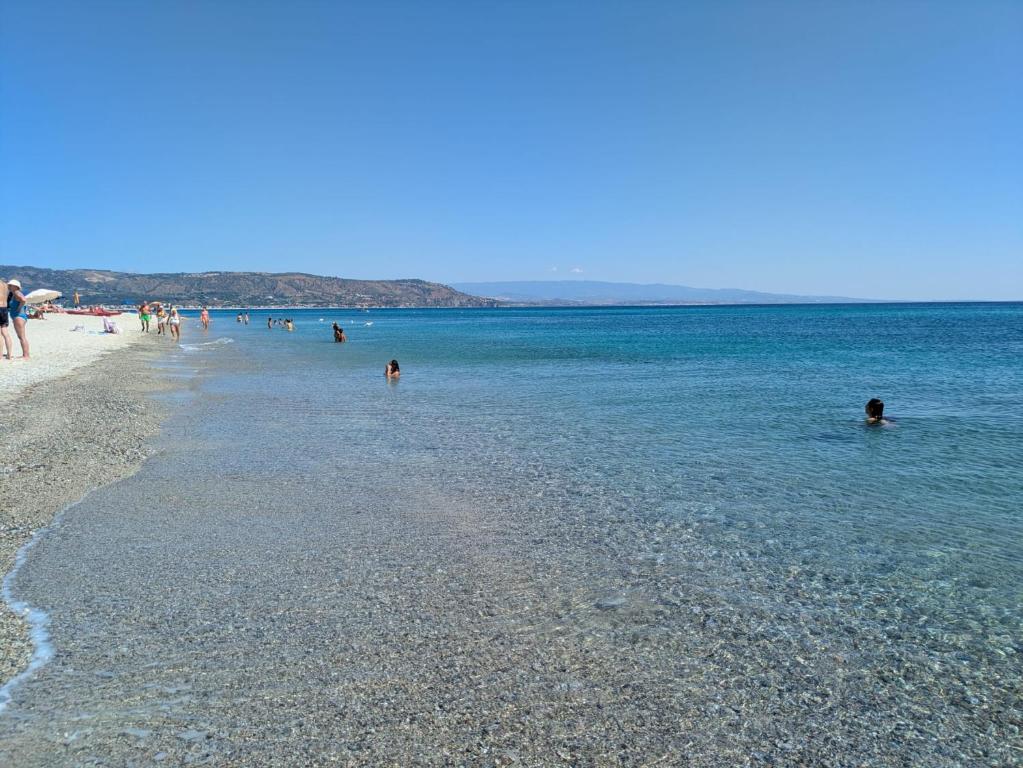 a group of people in the water on a beach at SeaYouSoverato Apartment in Soverato Marina