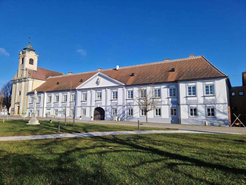 a large white building with a church in the background at Pfarrschlössl Sallapulka in Purgstall