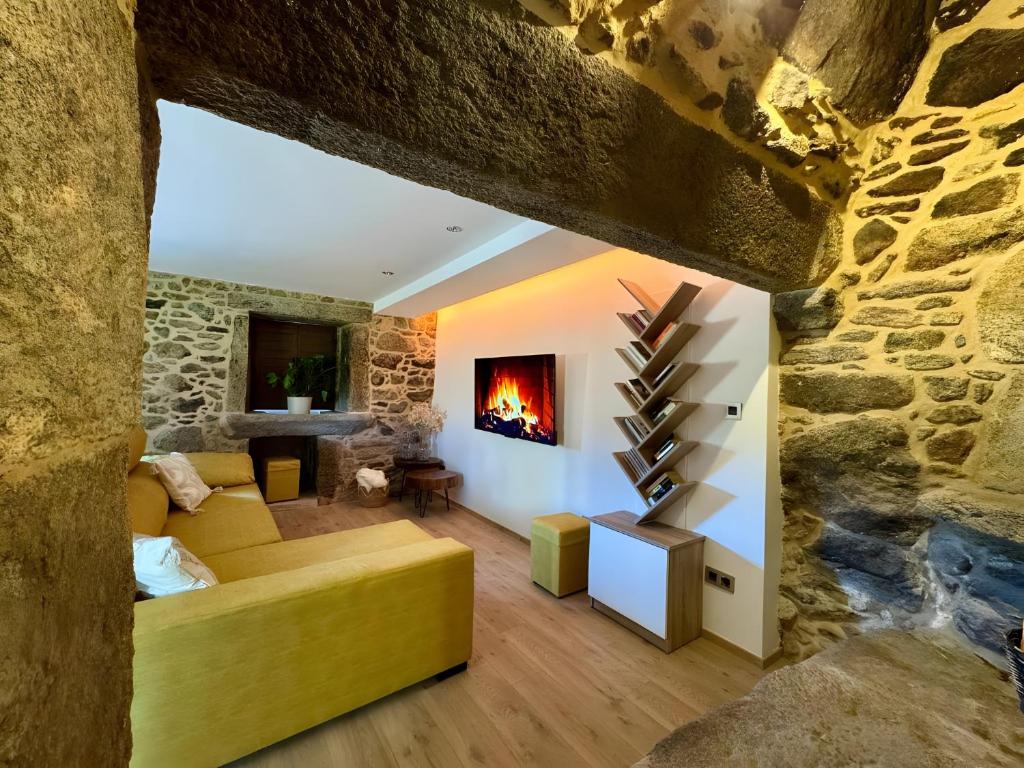 a living room with a fireplace in a stone wall at Mar Do Val in Muxia