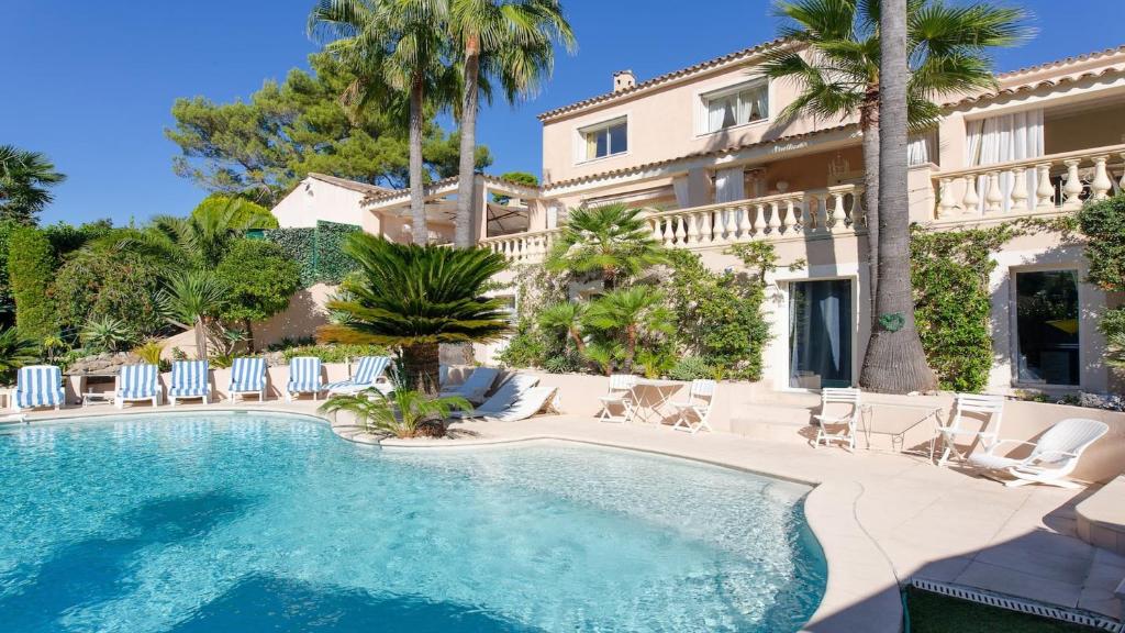 a swimming pool in front of a building with palm trees at 9 chambres spa hamman sauna Piscine chauffée poss in Juan-les-Pins