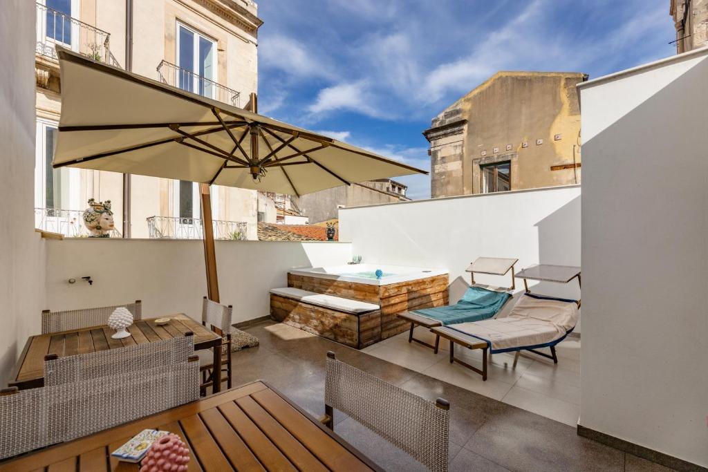 a patio with a table and an umbrella on a balcony at Rial Collection Luxury Suite in Syracuse
