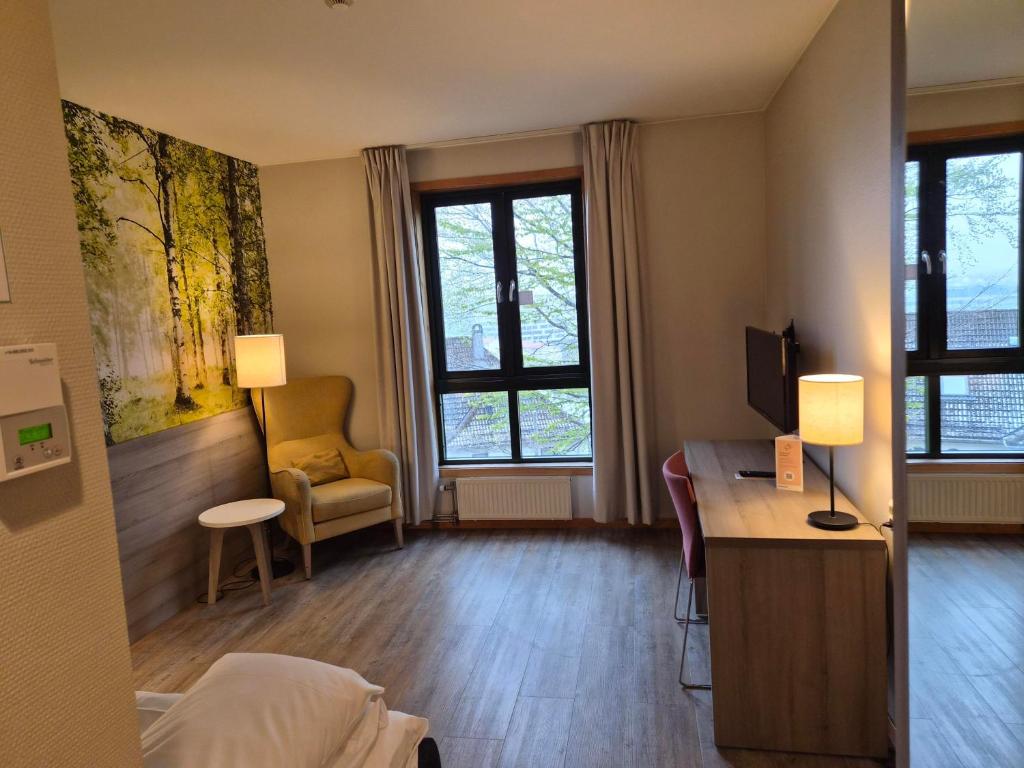 a hotel room with a bed and a desk and windows at Haukeland Hotell in Bergen