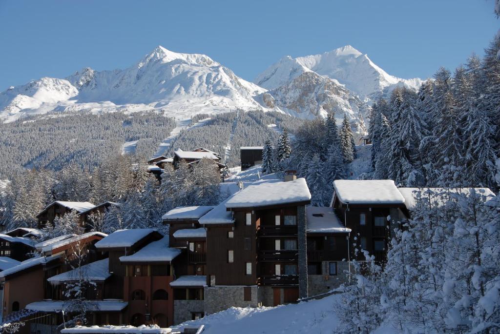 un edificio cubierto de nieve con una montaña en el fondo en GSI Les Coches en Les Coches