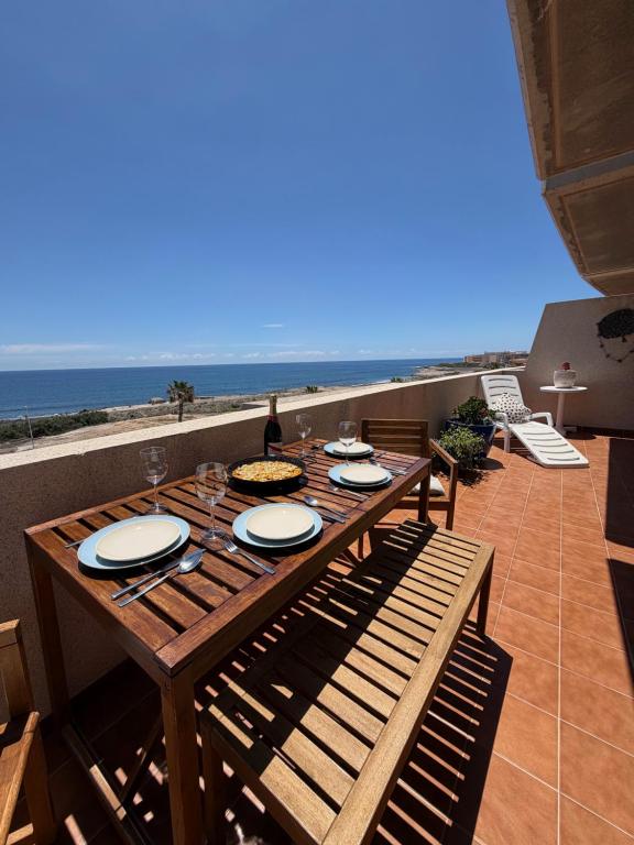 a wooden table with plates on it on a patio with the ocean at Fully equipped seaview Cabezo flat in El Médano