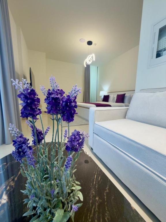 a vase with purple flowers on a table in a living room at Beautiful Studio Retreat in Ras al Khaimah