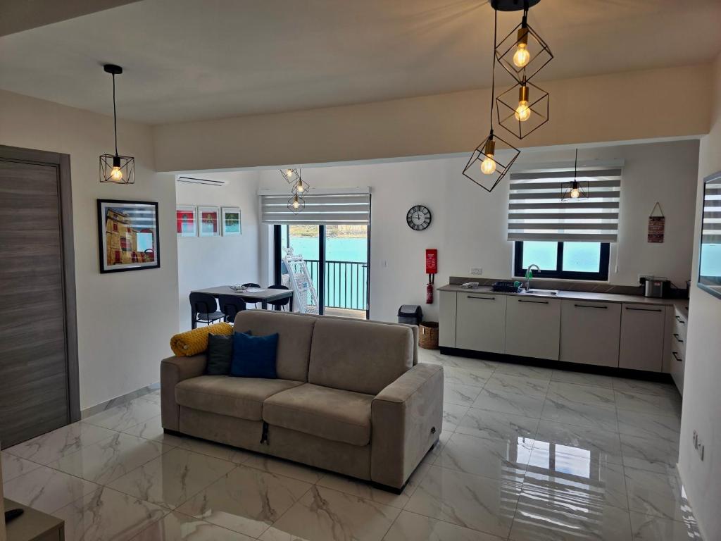 a living room with a couch and a kitchen at Coastline, Lovely Seafront Apartment in Birżebbuġa