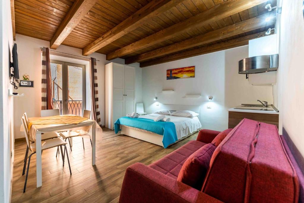 a living room with a red couch and a bed at Cefalù Center Apartments in Cefalù
