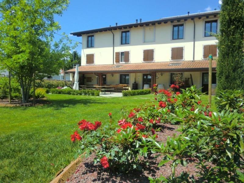 dom z czerwonymi kwiatami w ogrodzie w obiekcie Agriturismo La Rosta w mieście Cervignano del Friuli