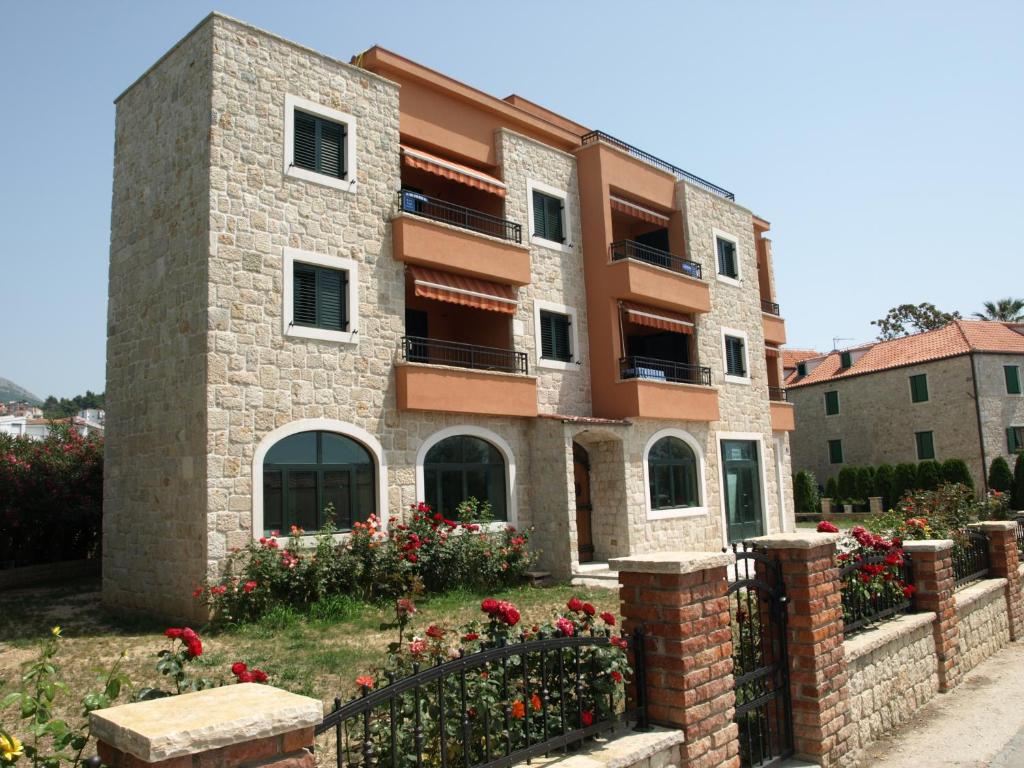 ein Gebäude mit einem Zaun und Blumen davor in der Unterkunft Apartment Vedran in Podstrana