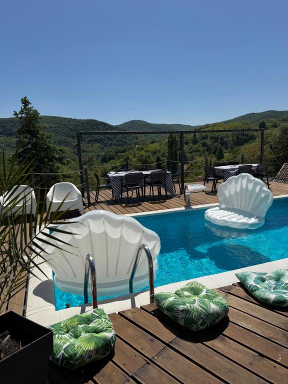 a swimming pool with two chairs and a table at Vila na Vrhu in Rakovac