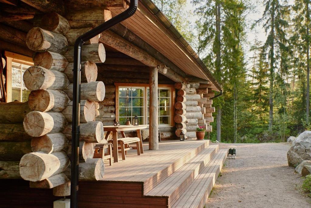a log cabin with a wooden porch and a table at Hawkhill Resort in Tervalampi