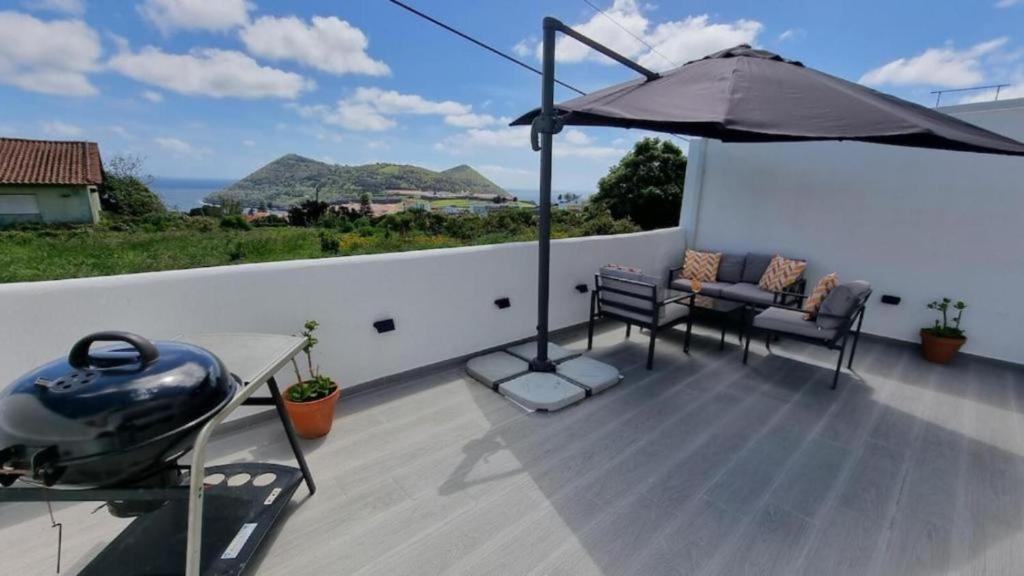 a patio with an umbrella and a table and chairs at Mar & Monte in Angra do Heroísmo