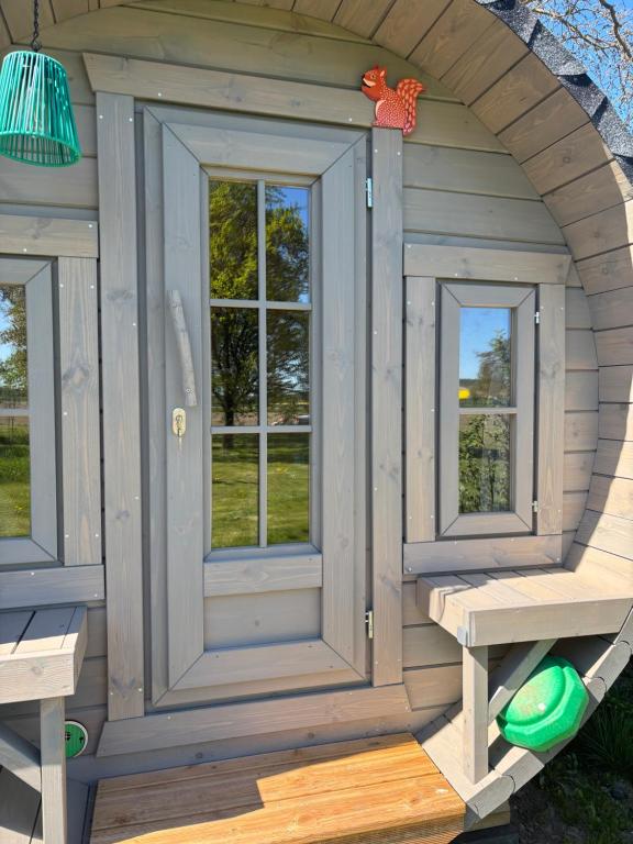 a wooden play house with two windows and a bench at Obstgarten im Warnetal- Campingfass Kobel in Gielde