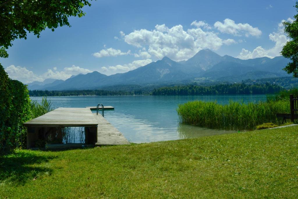 a dock on a lake with mountains in the background at Seepark Drobollach in Drobollach am Faaker See