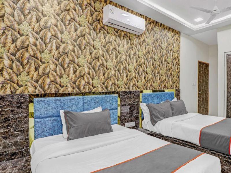 a room with two beds and a wall with a mural at HOTEL Sarovar in Ahmedabad