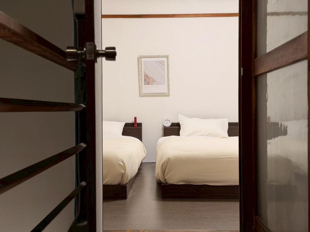 a bedroom with two beds and a door leading into a room at ura San Jose トリプルルーム in Okayama