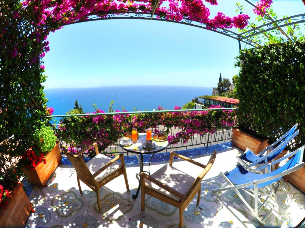 un patio con mesa, sillas y flores en Locanda Costa D'Amalfi en Amalfi