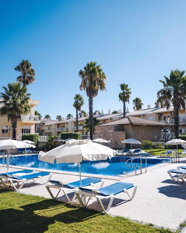 a swimming pool with lounge chairs and umbrellas at 1A The Apartment in Albufeira