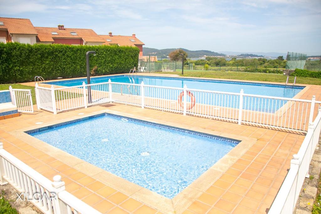 a swimming pool with a white fence around it at Xilgar - Chalet Ensenada de Lanzada in Sanxenxo