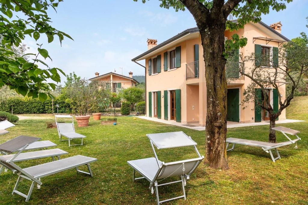 a group of lounge chairs and a tree in front of a house at Casa Alessandra in Torri del Benaco