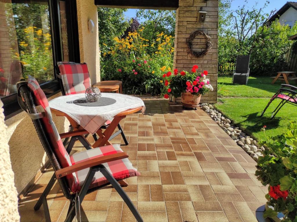 a patio with a table and chairs and flowers at Ferienwohnung Klaus in Ebermannstadt