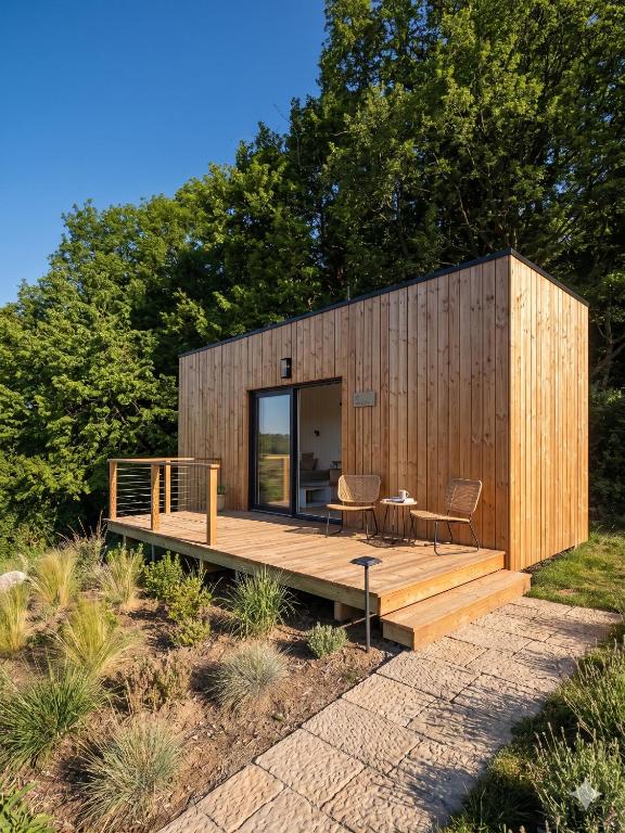 una piccola cabina di legno con tavolo e sedie su un ponte di Stuga a Érezée