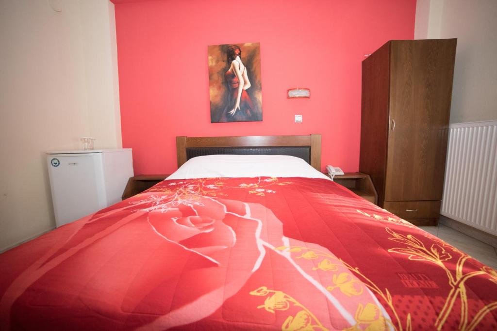 Un dormitorio con una cama con una pared rosa. en Hotel Galaxias, en Kato Loutraki