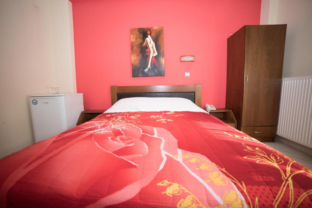 a bedroom with a bed with a pink wall at Hotel Galaxias in Kato Loutraki