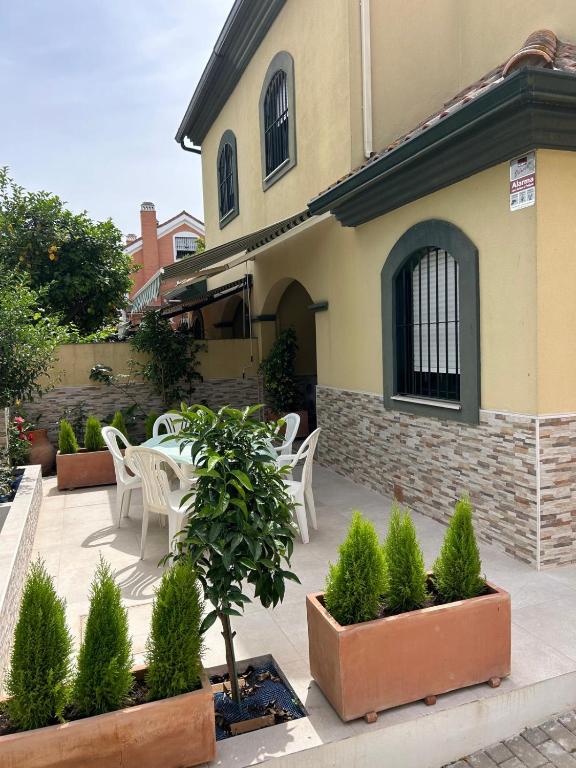 a patio with white chairs and plants in front of a building at WonderStays Chalet El Naranjo in Seville