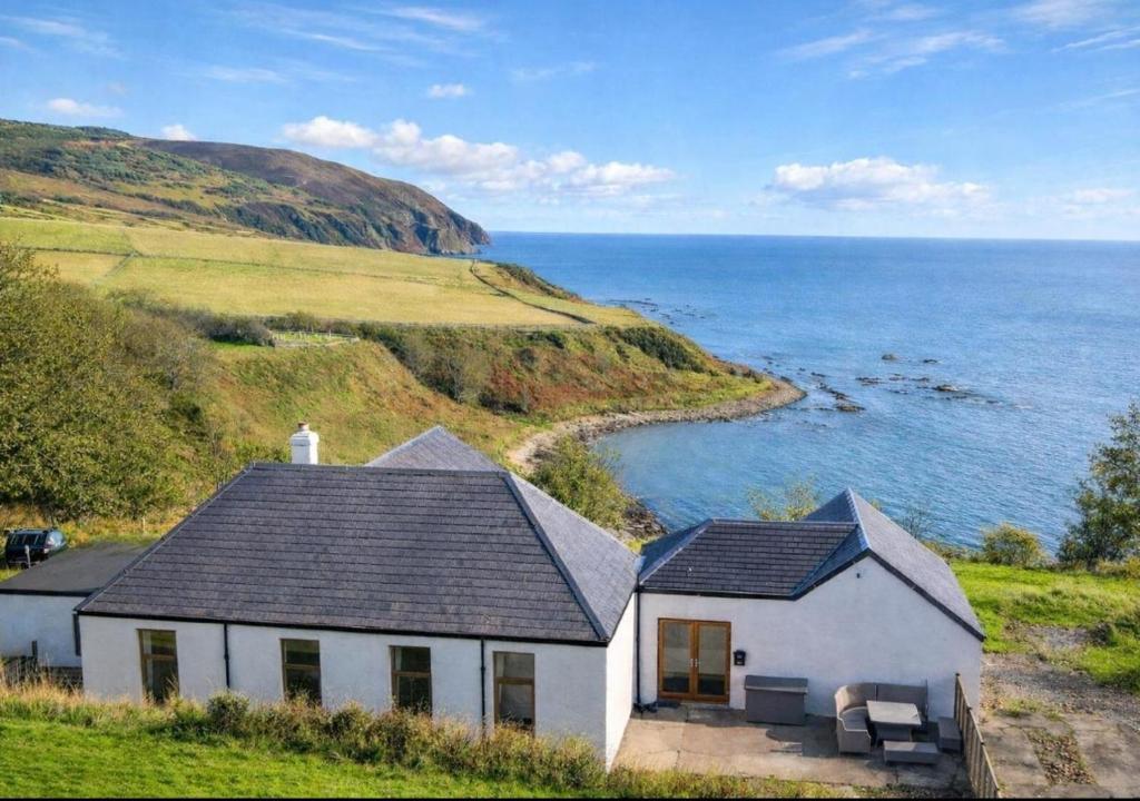 a white house on a hill next to the ocean at North Lodge - NC500 in Helmsdale