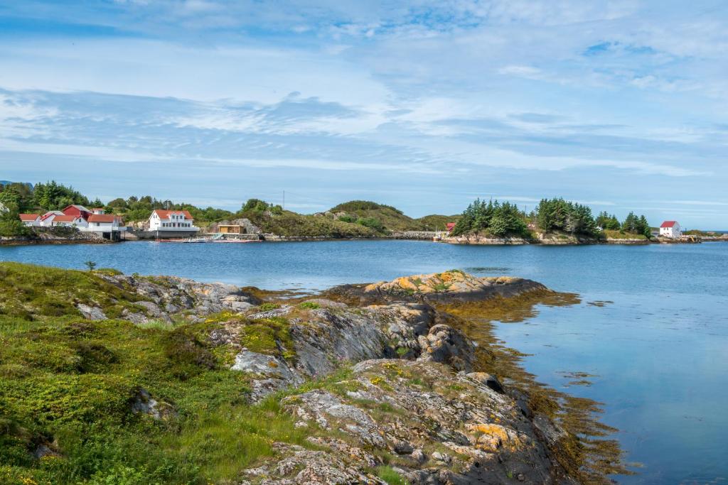 a large body of water with rocks and houses at Lysø naturcamping og rorbuer in Averoy